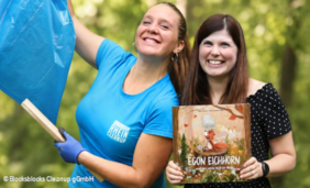 Foto von zwei jungen Frauen mit einem Müllsack und einem Kinderbuch: Team Blocksblocks Cleanup und Kinderbuchautorin Alina Gries
