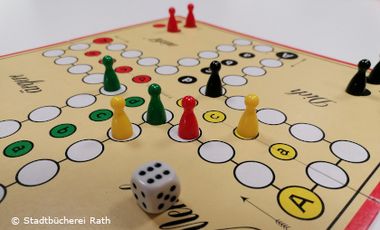 Foto vom Spielbrett mit Spielfiguren und Würfel des Spiels "Mensch ärgere Dich nicht"