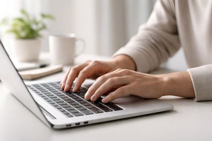 Mensch tippt mit zwei Händen auf Laptop-Tastatur