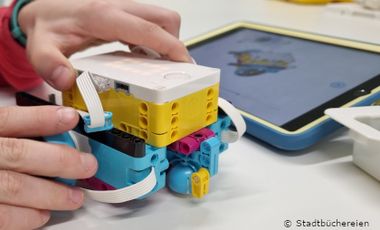 Foto von Kinderhand mit Lego-Spikes und Tablet PC.