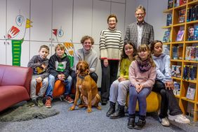 Zusammen mit den Schülerinnen und Schülern freuen sich Beigeordnete Miriam Koch (M.), Hundebesitzerin Carla-Maria Maaß und Dr. Norbert Kamp, Direktor Stadtbüchereien Düsseldorf, über das tierische Angebot in Wersten