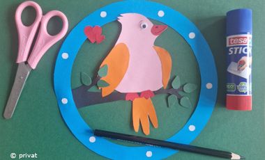 Foto mit einem Vogel aus buntem Papier, Kleber und Schere