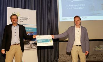 Michael Zyweck (Zukunftsnetz Mobilität NRW) überreichte die Urkunde für die Teilnahme an den Fußverkehrs-Checks 2020 an Florian Reeh (Amts für Verkehrsmanagement). Foto: Lammert