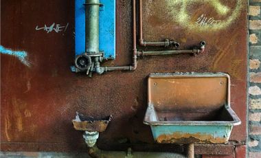 Fotografie mit Details verlassener Industriekulutur: alter Boiler, Waschbecken und rostige Rückwand.