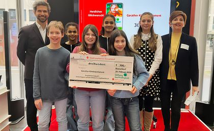 Foto von Kindern des Garather Kinderparlaments und Mitarbeitenden der Stadtsparkasse Düsseldorf