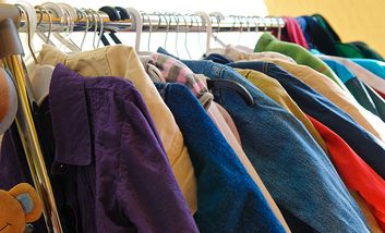 Foto mit Kleidung auf Bügeln an einer Kleiderstange