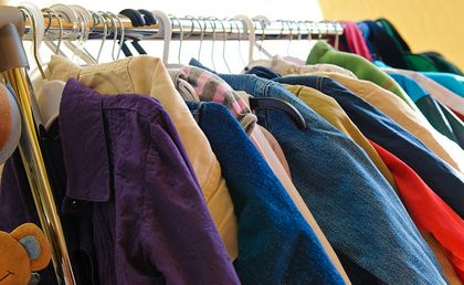 Foto mit Kleidung auf Bügeln an einer Kleiderstange