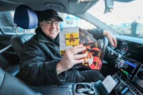 Taxifahrer Alex Mordoukhovitch mit den Kondom-Postkarten, die über die Karnevalstage an Fahrgäste verteilt werden. Foto: Michael Gstettenbauer