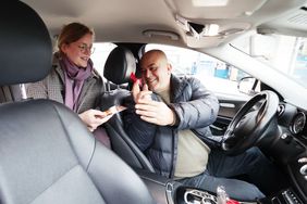 Taxifahrer Kamanli Cumhur während er eine Kondom-Postkarte an Jasmin Stellmacher übergibt. Foto: David Young