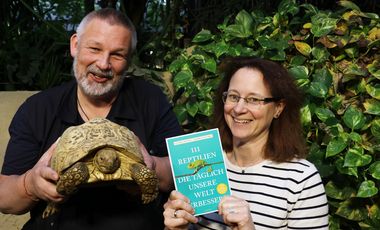 Das Autoren-Team im Schildkrötengehege. Markus Juschka hält eine Pantherschildkröte in die Kamera, Sandra Honigs das neue Buch. 