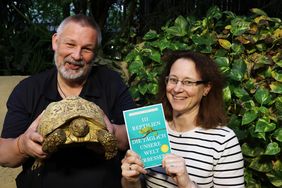 Das Autoren-Team im Schildkrötengehege. Markus Juschka hält eine Pantherschildkröte in die Kamera, Sandra Honigs das neue Buch. 