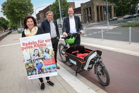 Foto von Oberbürgermeister Dr. Stephan Keller und Mobilitätsdezernent Jochen Kral die gemeinsam an einem Lastenrad stehen und Umweltdezernentin Helga Stulgies die ein Poster von Stadtradeln 2022 in der Hand hält.(v.r.).