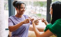 Zwei junge Frauen unterhalten sich in Gebärdensprache, Foto: iStock, Maria Vitkovska