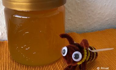 Gebastelte Biene mit Wackelaugen neben einem Honigglas.
