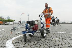 Ein Arbeiter trägt die Abstandskreise im Auftrag der Landeshauptstadt auf. Foto: David Young