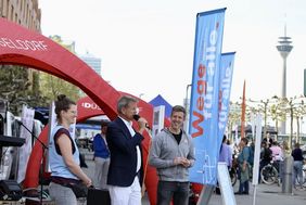 Foto der genannten Personen vor dem Stand der Landeshauptstadt Düsseldorf.