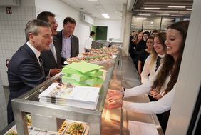 Tatkräftige Eröffnung (v.l.): OB Thomas Geisel, Eckhard Forst, Vorstandsvorsitzender der NRW.BANK, und Stadtdirektor Burkhard Hintzsche halfen in der neuen Mensa, die Schülerinnen und Schüler zu versorgen.