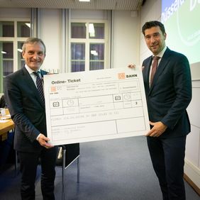 Ein Online-Bahnticket nach Den Haag überreichte Beigeordneter Robert van Asten aus Den Haag (rechts) an Oberbürgermeister Thomas Geisel. Foto: Gemeinde Den Haag/Martijn Beekman